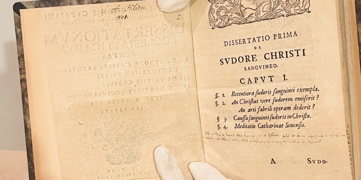 Hände mit weißen Handschuhen halten ein altes Buch aufgeschlagen  &copy;Stadtmuseum Jena